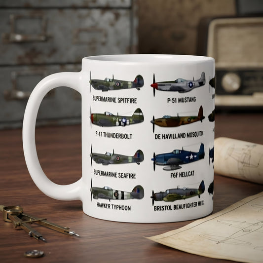 A white ceramic mug printed with multiple vintage fighter plane illustrations and their names, placed on a wooden desk with a blurred vintage radio, keys, and papers in the background.